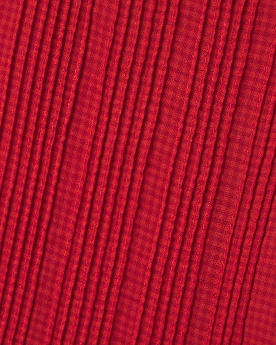 Close-up of the textured fabric on the Kinsley Blouse in Crimson Check by Trovata Birds of Paradis, showing parallel ridges and striped pattern. Lighting highlights the depth and detail of this 100% cotton blouse material.