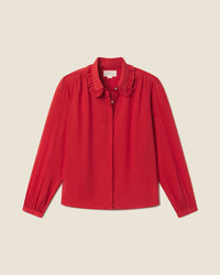 The long-sleeved Kinsley Blouse in Crimson Check by Trovata Birds of Paradis features a ruffled collar and button-down front, shown on a plain light beige background.