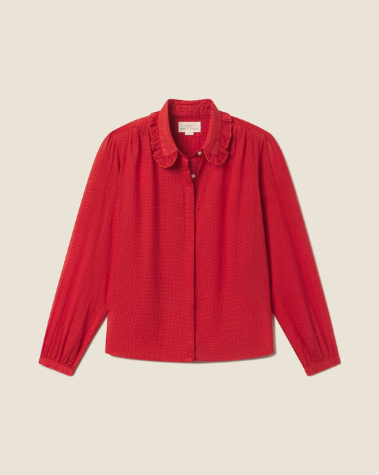 The long-sleeved Kinsley Blouse in Crimson Check by Trovata Birds of Paradis features a ruffled collar and button-down front, shown on a plain light beige background.