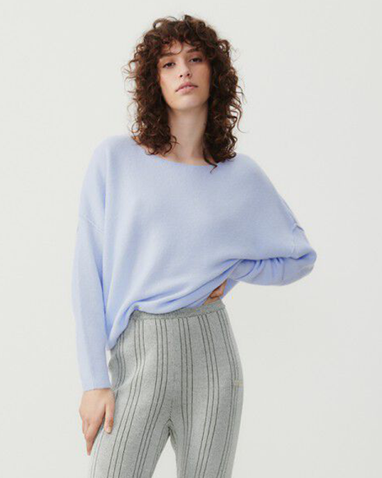 Woman posing in a light blue, American Vintage Damsville Boatneck Sweater in Alaska wool blend pullover and striped pants.
