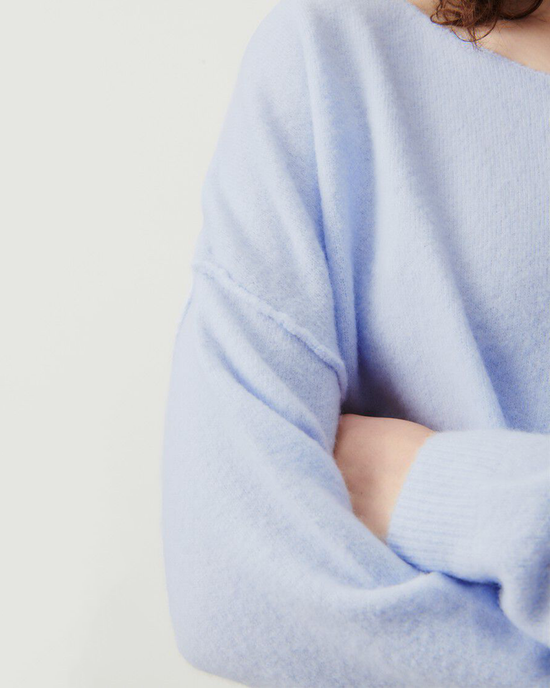 Person wearing a light blue Damsville Boatneck Sweater in Alaska with arms crossed from American Vintage.