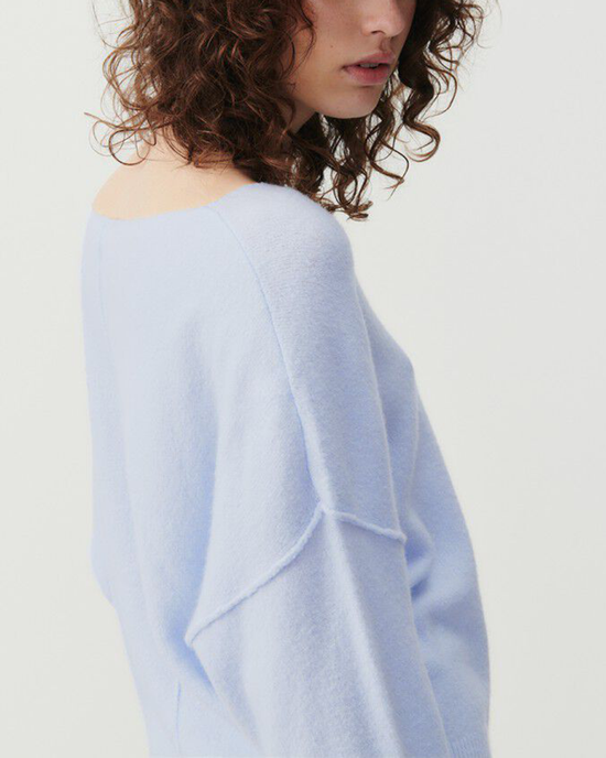 Woman in a light blue Damsville Boatneck Sweater in Alaska by American Vintage, with an off-the-shoulder, boatneck design.