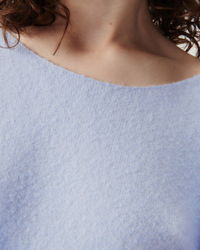 Close-up of a person wearing a light-colored, wool blend, American Vintage Damsville Boatneck Sweater in Alaska.