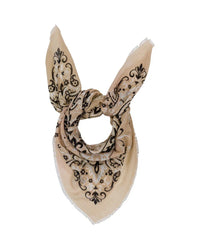 The Classic Wool & Silk Bandana in Beige by Maison Lecomte Flament features a black and white ornate floral pattern, folded into a triangular shape with pointed ends, displayed on a plain white background.
