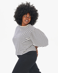 Woman posing with her hand on her hip, wearing a Clare V. Drop Shoulder Tee in Navy & Cream Stripe and black pants, smiling to the side.