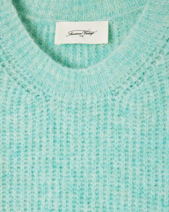 Close-up of a light blue East V Neck Sweater in Lagon Chine with an American Vintage brand label at the neckline, made from an American Vintage wool/alpaca blend.