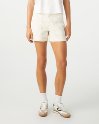 A person wearing AMO's Easy Army Short in Bone, white socks, and beige sneakers stands against a plain background.
