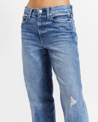 A close-up of a person wearing AMO's Billie Cropped Wide Straight in Warmth with a distressed detail on the right knee.