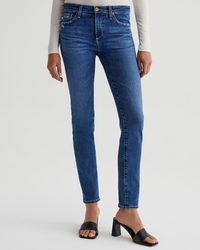 Woman wearing blue AG Jeans Empower Denim mid-rise jeans and black open-toe heels.