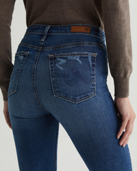 Close-up of a person wearing AG Jeans Farrah Boot in Brighton showing the back pocket detail.