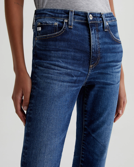 Close-up of a person wearing AG Jeans' Farrah Boot Crop in 8Ys East Coast, focusing on the upper part of the jeans with detailed stitching.