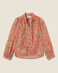 The Clara Blouse in Vermillion Vine by Trovata Birds of Paradis is a long-sleeved, button-down top with red and beige floral print, gathered shoulders, and cuffed sleeves, shown laid flat on a light background.