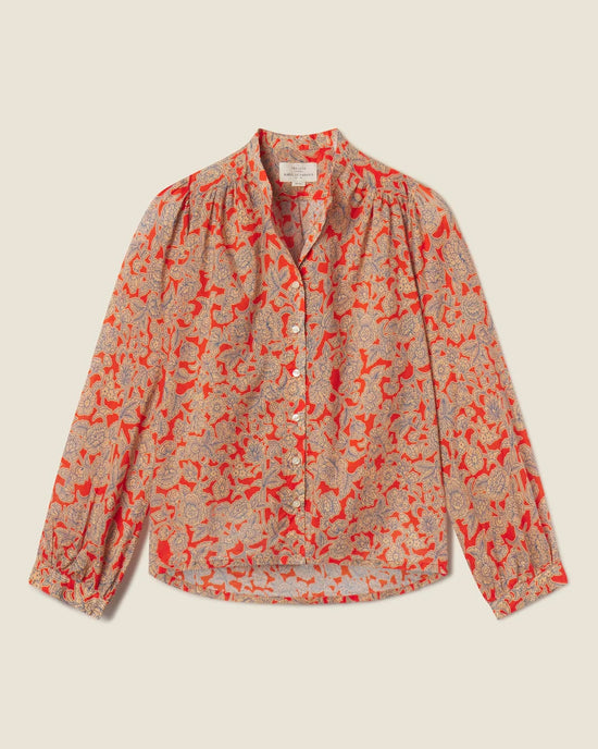 The Clara Blouse in Vermillion Vine by Trovata Birds of Paradis is a long-sleeved, button-down top with red and beige floral print, gathered shoulders, and cuffed sleeves, shown laid flat on a light background.