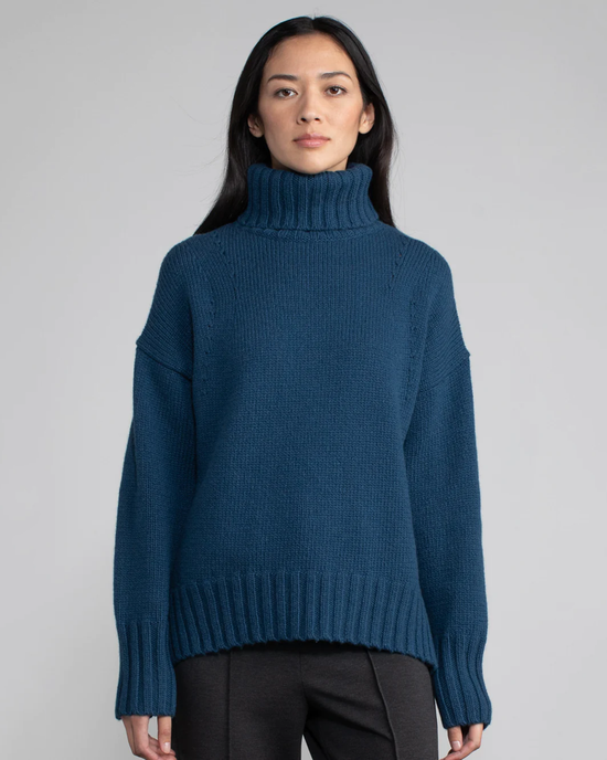 Woman posing in a Margaret O'Leary Vera Turtleneck in Oceanic cashmere sweater.