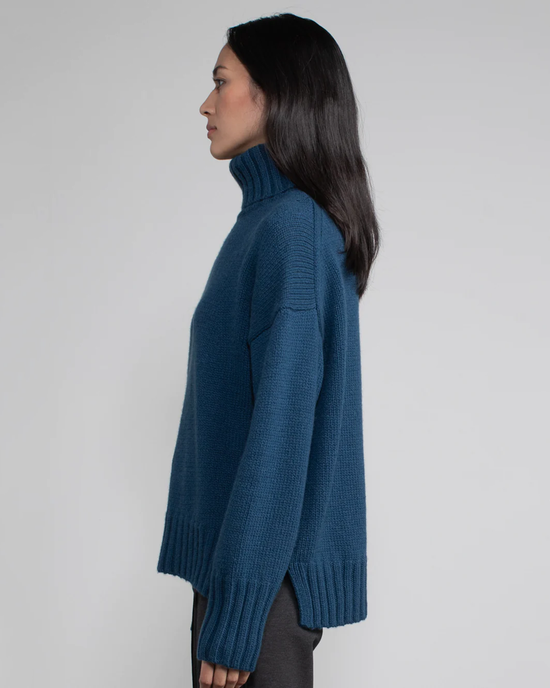 Side profile of a woman wearing a Margaret O'Leary Vera Turtleneck in Oceanic cashmere sweater.
