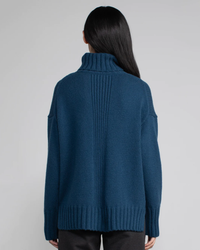 Woman wearing a blue cashmere Vera Turtleneck in Oceanic sweater by Margaret O'Leary viewed from the back.