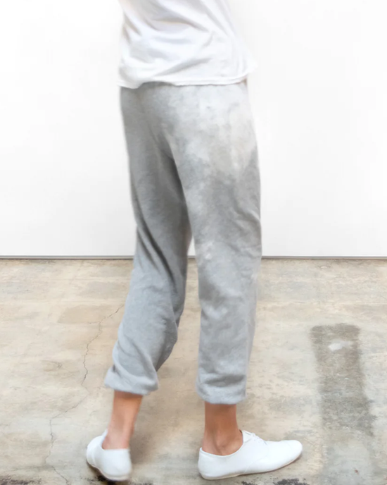 Person standing in grey Free City Bleachout Superfluff OG Sweatpants in Heather Bleachout and white sneakers against a plain background, sporting a matching set loungewear.