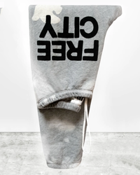 A pair of Bleachout Superfluff OG Sweatpants in Heather Bleachout from Free City with the words "oil free" printed upside down on one leg, displayed against a simple background.