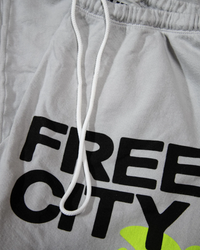 Close-up of gray French Terry sportswear with drawstring and the words "Free City" printed in black, Made in USA.