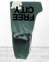 Large Sweatpant in Surplus Greens from Free City with "clique" graphic print hanging on a wall, crafted from French Terry.