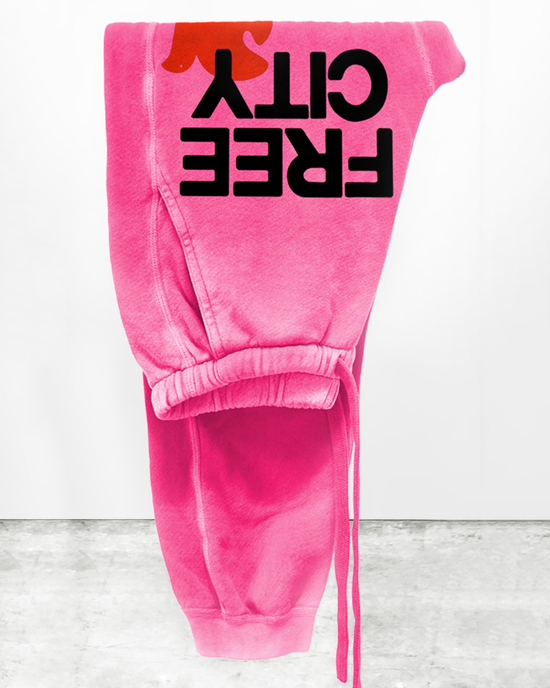 Large Sunfades Pocket Sweatpant in Pink Plant by Free City hanging on a wall, featuring "girl power" text displayed upside down and made from French Terry.