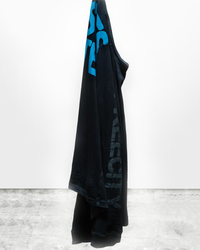 A black Free City AW Supervintage L/S Tee in Superblack Blue hanging and draping against a white wall on a gray floor, made of 100% Cotton.