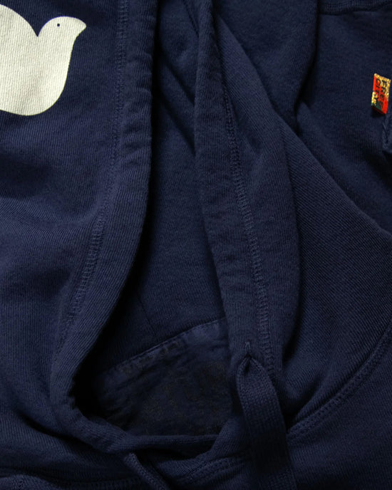 A close-up of the Free City Basic Goodness Hoodie in Moonshrooms shows a white bird graphic, colorful seam tag, and quality drawstring and stitching details on this light terry hoodie.