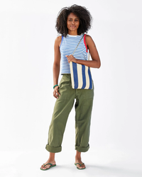 Woman posing in striped top and green trousers with a Clare V. Woven Racing Stripe Foldover Clutch w/ Tabs in Indigo & Cream.