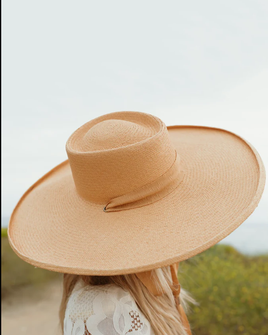 Woman wearing a Freya Sunbeam in Dijon broad-brimmed straw hat outdoors.