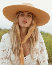 A woman in a white lace garment and a hand-woven Freya Panama hat.