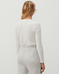 A woman seen from behind wearing an American Vintage Gamipy L/S Top in Blanc and grey pants.