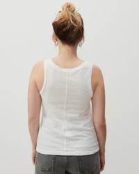 Rear view of a person with a bun hairstyle wearing an American Vintage Gamipy Scoop Tank in Blanc made of organic cotton and gray shorts against a neutral background.