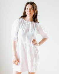 Woman standing against a white background, wearing a Kailani 3/4 Puff Slv Dress in White by Velvet by Graham & Spencer with puffed sleeves, and her hand on her hip.