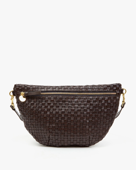 A small, dark brown Grande Fanny in Kalamata natural woven leather clutch with a gold zipper and a detachable chain strap by Clare V., isolated on a white background.