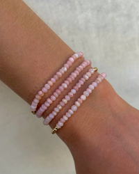 A person's wrist adorned with the 3MM Sig Bracelet with Pink Opal & Yellow Gold from Karen Lazar Design.