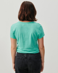 Woman seen from behind wearing a Jacksonville U Neck Tee in Diabolo Vintage by American Vintage in green and black jeans.