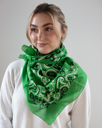 A person wearing a Maison Lecomte Flament Classic Cotton Bandana in Vert and a white top stands against a plain background.