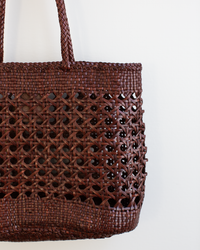 A close-up of the Dragon Diffusion Eclipse Bag in Bruciato, a handwoven brown tote with a detailed lattice pattern in supple buffalo leather, displayed against a plain white background.