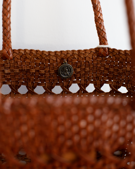 Close-up of the Dragon Diffusion Eclipse Bag in Tan woven leather, featuring a round metallic charm near the handle.