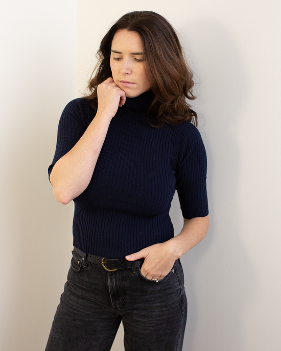 A woman in the Autumn Cashmere Cropped Elbow Sleeve Rib Turtleneck in Navy.