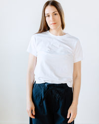 Woman wearing a Beaumont Organic Maliah Organic Cotton T-Shirt in White and navy trousers against a plain background.