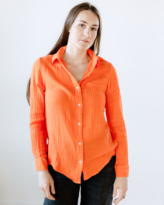 A woman in an orange Boyfriend Shirt in Cherry by Felicite Apparel standing against a white background.