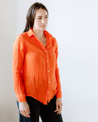 Woman in an orange Boyfriend Shirt in Cherry from Felicite Apparel standing against a neutral background.