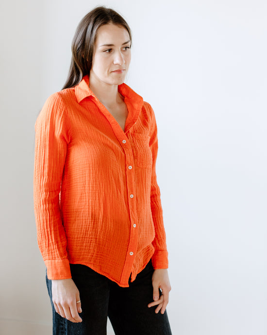 Woman in an orange Boyfriend Shirt in Cherry from Felicite Apparel standing against a neutral background.