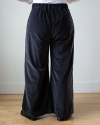 Person standing in Polly Wide Leg Pant - Cotton Velvet in Carbon by CP Shades against a white wall.