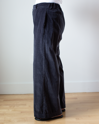 A person standing sideways wearing CP Shades Polly Wide Leg Pant - Cotton Velvet in Carbon and brown shoes.