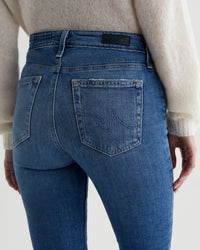 Close-up of a person wearing AG Jeans Mari Crop in Alibi Destructed showing details of the back pockets and waistband.