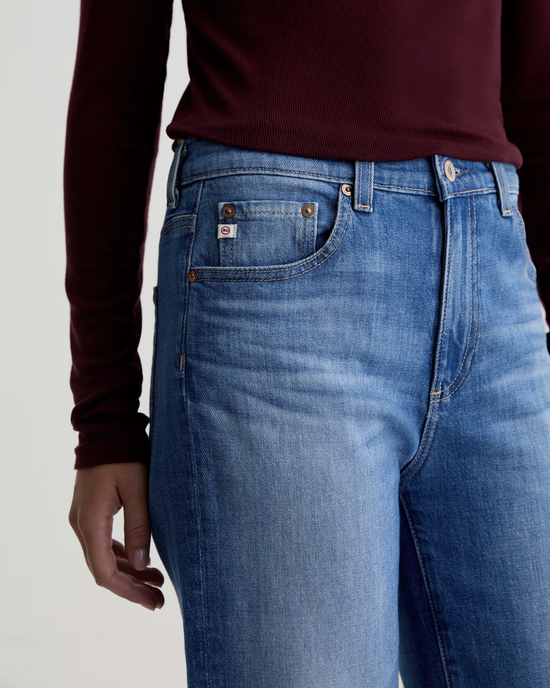A person wearing AG Jeans' The Brinley Straight in 13Ys Allure, a mid-rise straight jean in classic blue.