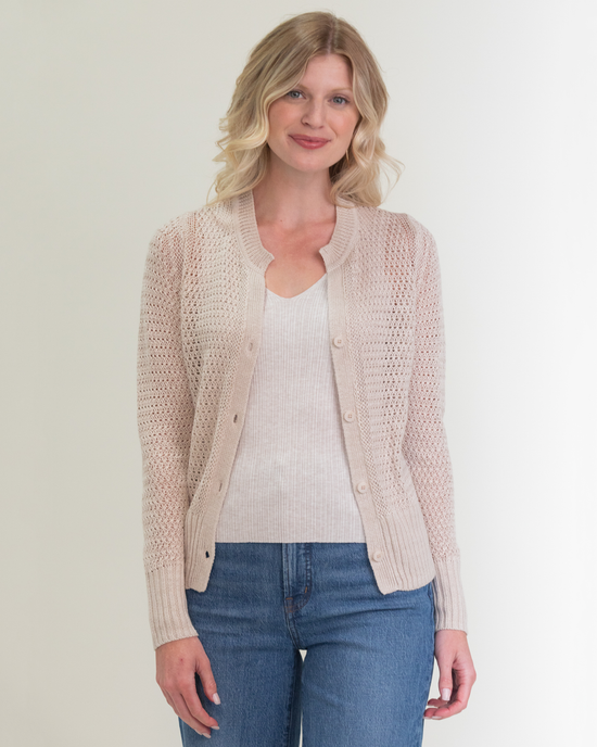 Woman wearing a Margaret O'Leary Elodie Cardigan in Natural with a white top and blue jeans standing against a neutral background.