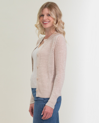 Woman smiling in casual attire with a 100% Linen Margaret O'Leary Elodie Cardigan in Natural and blue jeans.